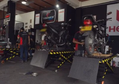 Mecánico revisando una motocicleta en el elevador del taller Toches Motos